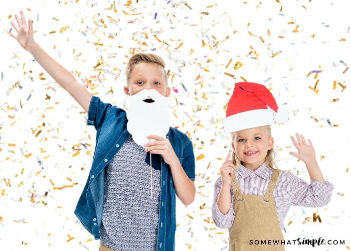 two kids holding santa picture props with gold confetti falling
