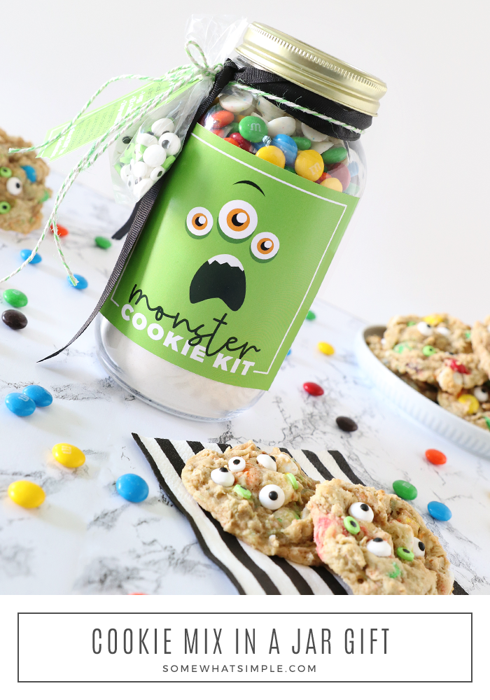 monster cookie mix in a mason jar with finished cookies sitting next to the jar
