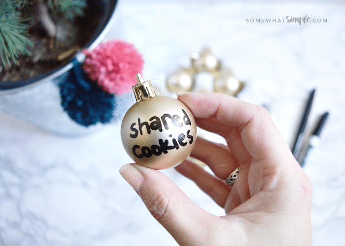 a gold ornament with a kind act written in black marker