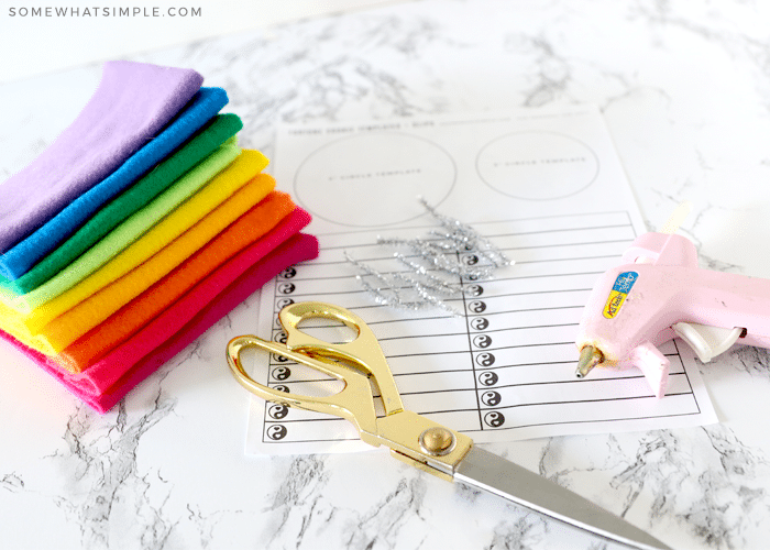 felt, scissors, hot glue gun and paper on the counter to make felt fortune cookies