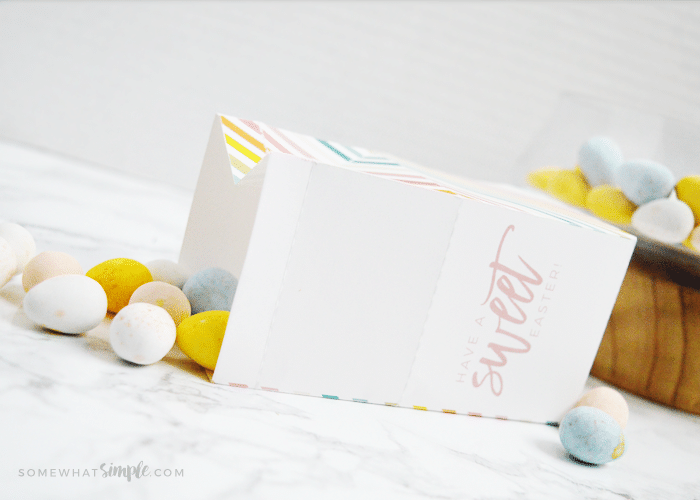 easter treat box laying on its side with candy eggs spilling out