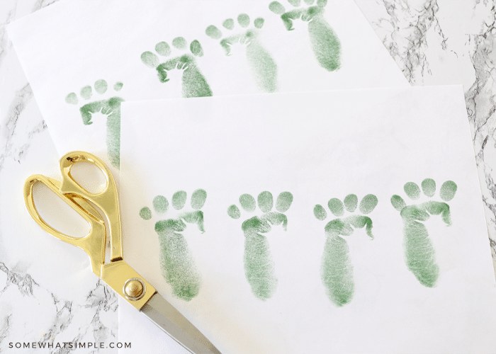 gold scissors next to a paper of green leprechaun footprints