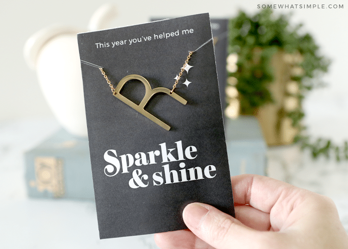 holding a card with an initial necklace for the teacher