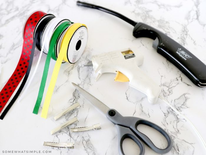ribbon, scissors, glue gun and lighter on the counter