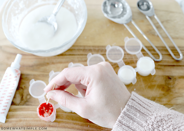 adding red food coloring to a paint pot and mixing with toothpick