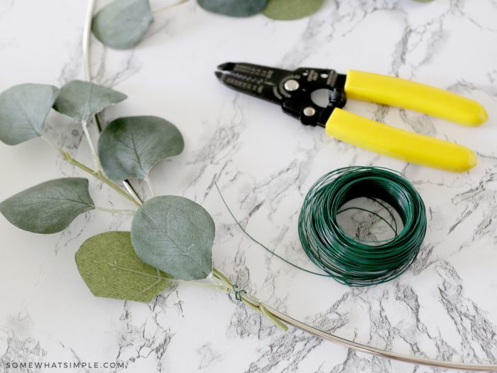 placing greenery on a wreath form with wire
