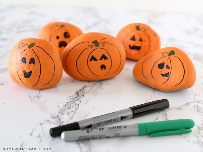 adding faces to river rock pumpkins with black and green sharpie markers