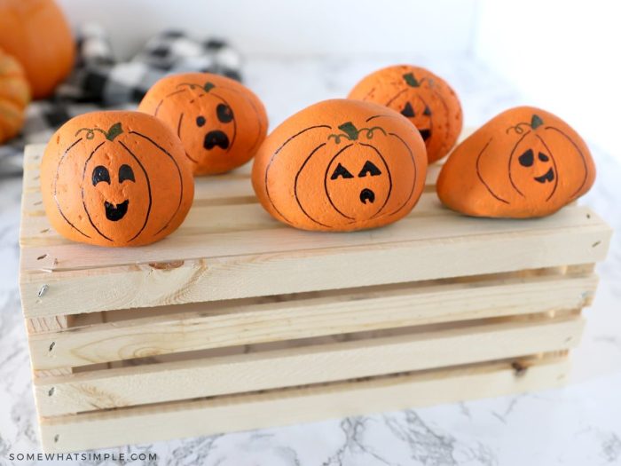 five little pumpkins made from river rock on a wood crate