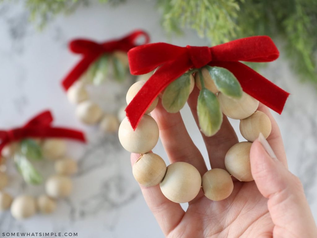 holding an ornament made from wood beads