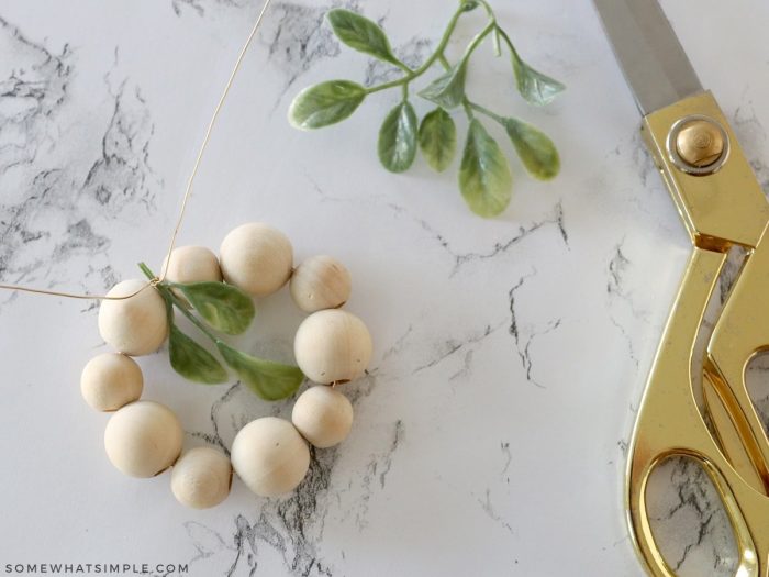 adding greenery to a wood bead ornament