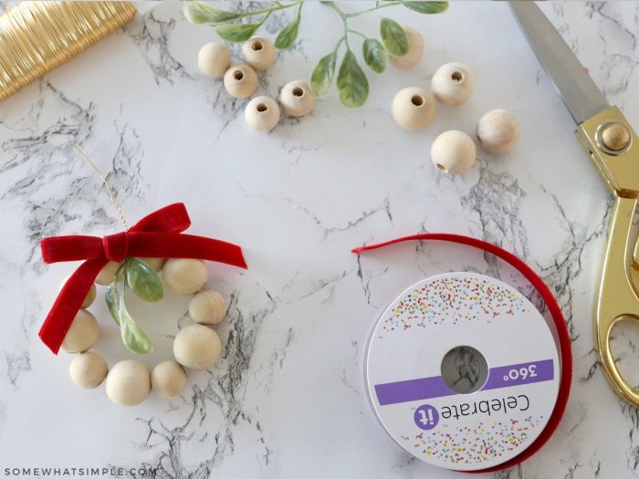 adding a ribbon to a wood bead ornament wreath