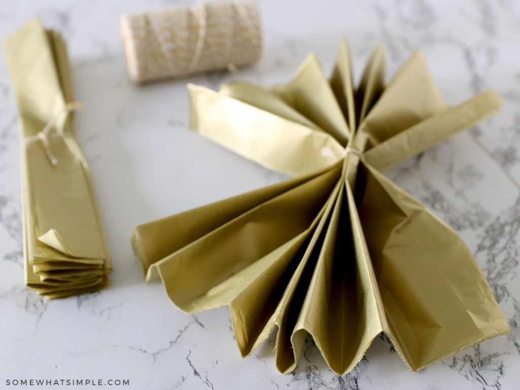 putting string in the center of an accordian folded stack of tissue paper