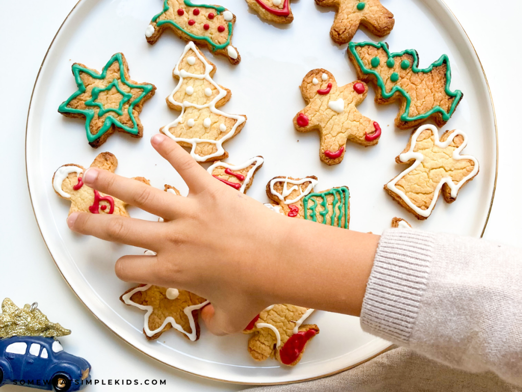 child's hand over. aplate of christmas cookies