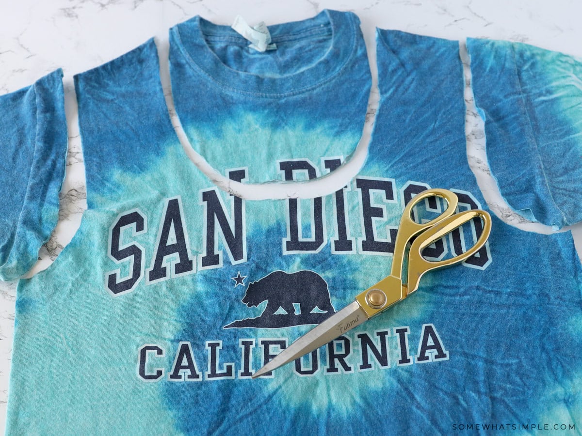 cutting the neck and sleeves of a t shirt to make a tote