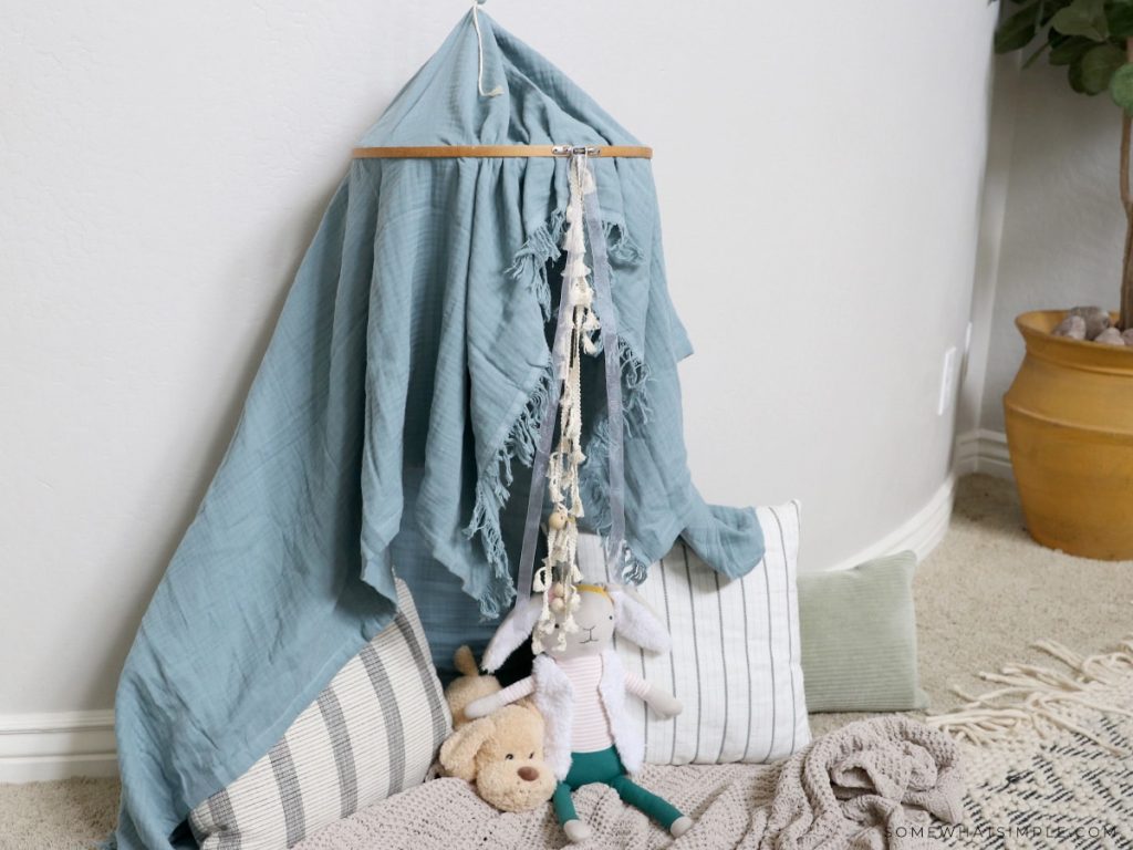 hanging play tent with stuffed animals and blankets on the floor