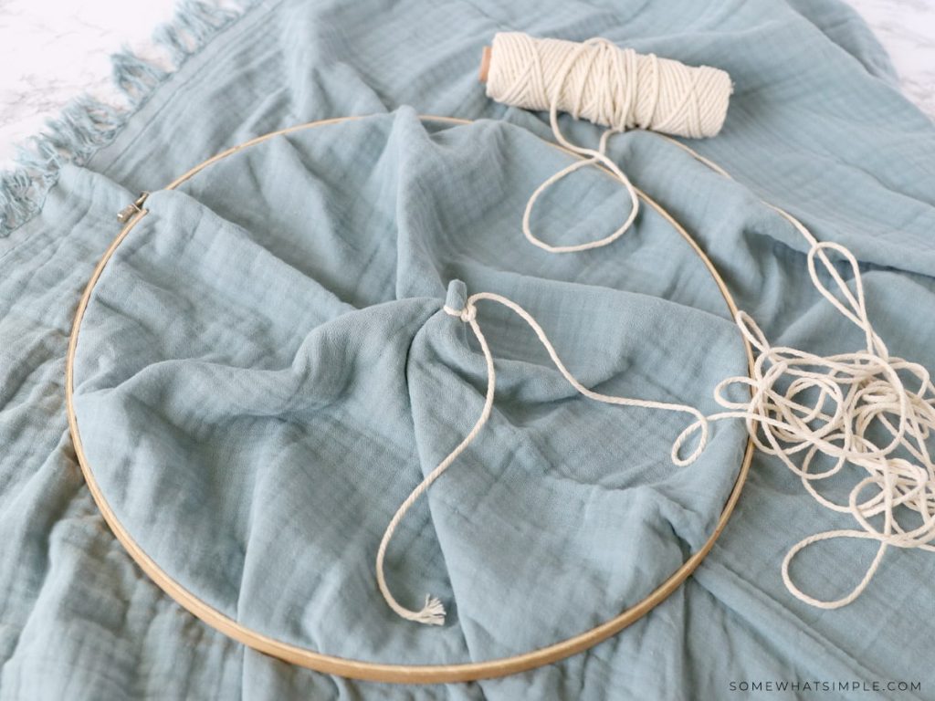 tying a knot with string around some fabric to make a hanging play tent