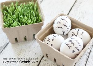 two berry crates with fake grass and white easter eggs written on with a sharpie