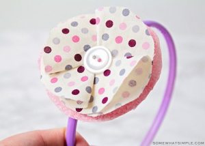 purple and pink headband with fabric flower on the side and a button in the center